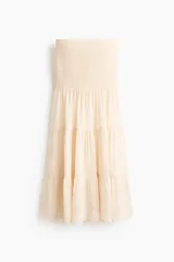 Pollera maxi de gasa color beige con efecto arrugado, con sección de punto smock en la cintura y diseño de volados escalonados en la parte inferior.