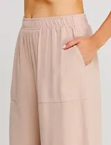 Pantalón palazzo de tiro alto color beige, confeccionado en mezcla de lino y viscosa, con silueta suelta y fluida, cintura elastizada, bolsillos delanteros aplicados y ruedo festoneado de corte tobillero.