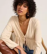 Blusa color crema con escote en V, mangas largas y lazo en el busto.