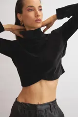 Polera corta de terciopelo negro, con cuello alto y mangas largas.