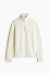 Buzo de punto acanalado con cuello elevado y cierre frontal parcial. Presenta un diseño de corte estándar con puños y bajo de acabado acanalado.