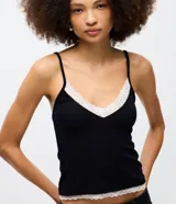 Musculosa de rib color negro, con breteles finos y escote en V con detalle de encaje blanco en el borde superior y en el ruedo.