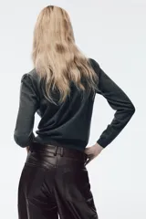 Chaqueta de punto gris oscuro con cuello solapa y manga larga. Presenta un diseño frontal con detalle de puntilla en color crema a contraste y cierre con botones.