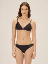 Conjunto de bikini negro de textura acanalada con sutiles destellos brillantes, compuesto por un corpiño triangular con detalle de volado lateral y una bombacha clásica tipo vedetina.