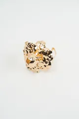 Brazalete rígido de diseño floral con acabado metálico martillado en color dorado.