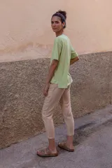 Pantalón chino color beige de lino y viscosa, con bordado de palmeras en verde claro. Tiene tiro medio-alto, pierna recta y bolsillos laterales y traseros.