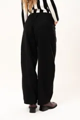 Pantalón de tiro medio con silueta curvada, más ancha en la zona de los muslos y rodillas, con cierre frontal de cremallera y botón.