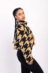 Campera corta de polar color beige con estampado de estrellas negras, cuello alto y cierre frontal.