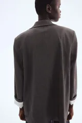 Blazer de sarga con diseño a cuadros, solapas de pico y frente abierto. Cuenta con bolsillos delanteros ribeteados con solapa y mangas diseñadas para ser remangadas, revelando un forro a rayas. Prenda completamente forrada.