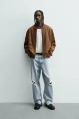 Cazadora bomber negra de corte regular fit, confeccionada en tejido efecto ante. Cuenta con cuello, puños y bajo en rib elástico, manga larga, bolsillos de vivo en la cadera y un bolsillo interior. Cierre frontal con cremallera.