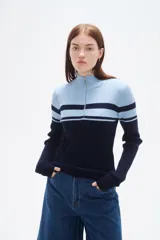 Polera de punto acanalado con diseño bicolor en blanco y negro, cuello alto con cierre frontal y manga larga.