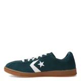 Championes Converse All Star Classic Trainer confeccionados en gamuza color verde petróleo, con el icónico logo de estrella y chevron en blanco en el lateral, cordones blancos y suela de goma color caramelo.