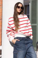 Buzo blanco con rayas horizontales rojas, de corte holgado y cuello redondo.