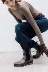 Bota tipo Chelsea de cuero vacuno color suela, con diseño brogue en la puntera y laterales. Presenta paneles elásticos laterales en color marrón oscuro, tirador trasero y suela de goma con plataforma.