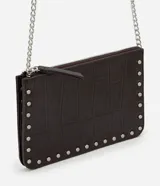 Cartera bandolera Satinato de color marrón oscuro, confeccionada en poliuretano con textura geométrica símil cocodrilo y detalles de tachas metálicas plateadas en los bordes. Cuenta con cierre superior y correa larga de cadena metálica.