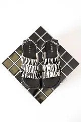 Sandalias chatas con tiras de cuero con estampado de cebra y base cuadrada.