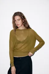 Jersey de punto fino con cuello redondo y manga larga con puños elásticos. Presenta un diseño minimalista con costuras visibles en los hombros.