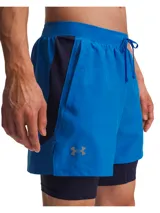 Shorts deportivos Under Armour 2 en 1, compuestos por un short exterior ligero de color azul y un short de compresión interior integrado de color azul marino. Presenta cintura elástica con cordón, bolsillos laterales y logotipo reflectante.