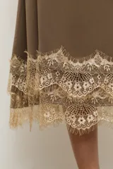 Falda midi color topo, confeccionada en tela fluida, con detalle de encaje en tono crudo en el ruedo.