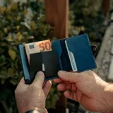 Billetera tipo tarjetero de cuero negro con caja de aluminio interna y sistema de deslizamiento para tarjetas. Cuenta con cierre mediante broche a presión.