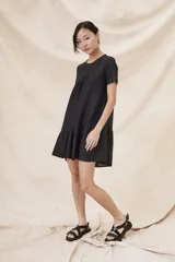 Vestido negro corto con cuello redondo, mangas cortas y falda con volantes.