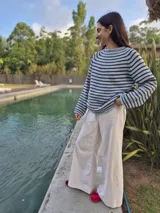 Sweater de tejido de punto con rayas horizontales alternando azul celeste y marrón oscuro. Presenta cuello redondo y mangas largas con caída.