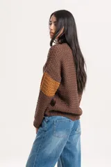 Buzo de tejido de punto con diseño combinado en tonos marrón y ocre, de cuello redondo y manga larga.