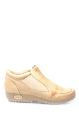 Zapato bajo de cuero color beige, con paneles elásticos laterales para un calce fácil y suela de goma dentada con logo grabado en el talón.