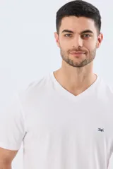 Remera básica de corte clásico, color blanco, con escote en V y mangas cortas. Presenta un pequeño logo bordado en el pecho.
