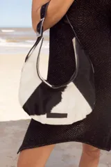 Cartera negra de cuero con forma de medialuna y tachas en zigzag.