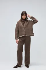 Cardigan de tejido de punto con textura, silueta boxy y cuello en V. Presenta cierre frontal con botones y detalles de terminación en contraste de color en los bordes.