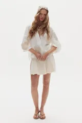 Minifalda blanca de denim con diseño evasé, godets que aportan movimiento y ruedo desflecado.