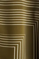 Camisa verde militar con estampado geométrico de líneas blancas, cuello clásico, botones frontales y mangas largas con puños abotonados.