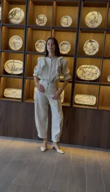 Pantalón de lino color beige, de corte tipo babucha con pinza central, bolsillos laterales ocultos y ajuste en el tobillo.