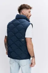 Cazadora acolchada de color azul marino con diseño de costuras onduladas, cierre frontal con cremallera y cuello alto. Presenta bolsillos frontales y un ajuste cómodo.
