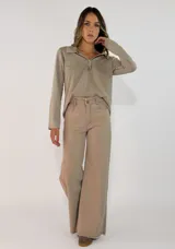 Pantalon de corte recto y tiro medio, confeccionado en gabardina color marrón. Presenta cierre frontal con botón y bolsillos laterales.