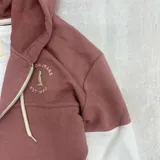 Campera con capucha color rosa viejo con mangas blancas, cierre frontal y bolsillos laterales.