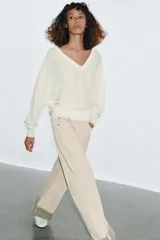 Jersey de punto color blanco crema, con escote en pico, manga larga y sisa ancha terminada en puño.