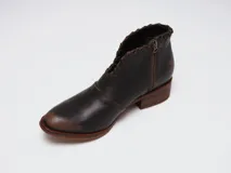 Botinetas de cuero color marrón con efecto desgastado en la puntera y el talón. Presentan un diseño con corte en V en el empeine con detalles de costuras decorativas, cierre lateral y taco bajo de madera.