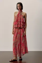 Falda larga de corte fluido con estampado paisley en tonos rojos, naranjas y celestes. Cuenta con cintura elástica y viene con un cinturón de cuero marrón con hebilla metálica dorada.