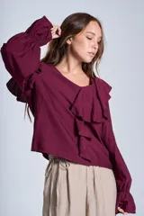 Blusa de color marrón con escote en V, mangas largas abullonadas con puños elásticos y detalles de volados en los hombros y el frente.