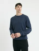 Sweater de tejido de punto con escote redondo y manga larga, con detalles de costuras en sisas y cuello. Presenta un diseño clásico y versátil.