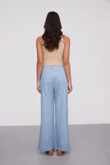 Pantalón celeste de algodón, de tiro alto y corte ancho, con cintura elástica ajustable mediante cordón y aberturas laterales en los bajos.