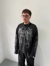 Remeron oversize de algodón pesado color negro con estampado gráfico en serigrafía gris en el frente y en ambas mangas. Presenta cuello redondo y grifa de la marca en el puño.