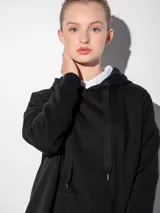 Canguro negro oversize con capucha ajustable con cordones y bolsillo tipo canguro en el frente.