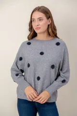 Sweater de punto gris con estampado de lunares oscuros, cuello redondo y mangas largas con puños acanalados.
