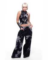 Pantalón de denim negro con estampado batik gris, corte sastrero de pierna ancha, tiro alto y pretina cruzada.