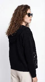 Campera de corte relajado color crema, con cierre frontal completo y cuello tipo bomber. Presenta dos bolsillos frontales destacados con apliques de lentejuelas blancas.