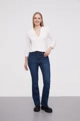 Pantalon jean de tiro alto con corte flare y terminación desflecada en el ruedo. Presenta un diseño clásico de cinco bolsillos con costuras en contraste.