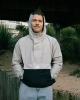 Rompevientos gris y negro de tela náutica, con cierre escondido en cuello alto y tres bolsillos de gran capacidad.